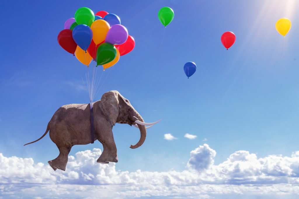 Elefant schwebt an Luftballons durch blauen Himmel